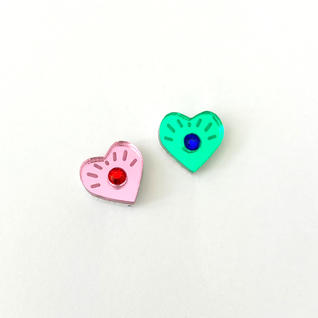 Mismatcehd eye heart studs with crystals in the center on a white background