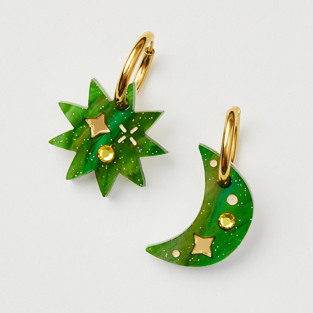 Green mismatched star and crescent earrings with twinkling motifs and a dazzling crystal inlay hanging on a gold hoop 