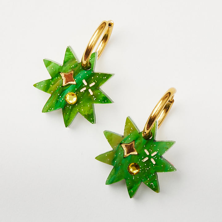 Green Star earring with twinkling motifs and crystal inlay hanging on a gold hoop  pictured on a model