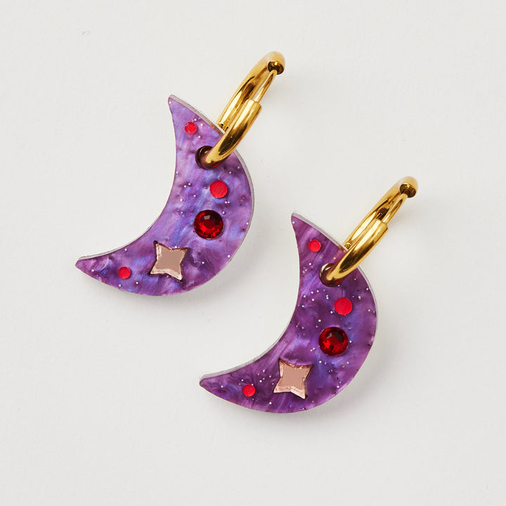 Purple Moon earring with twinkling motifs and red crystal inlay hanging on a gold hoop 