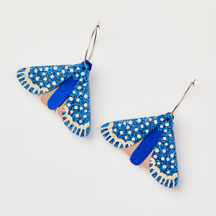 Martha Jean Moth Earrings - Indigo blue  glitter with rose gold on white background