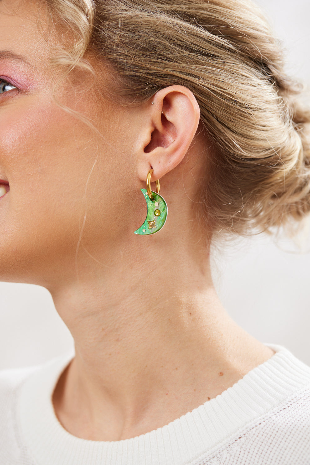 mismatched crescent moon earrings with twinkling motifs and a dazzling crystal inlay hanging on a gold hoop pictured on a model