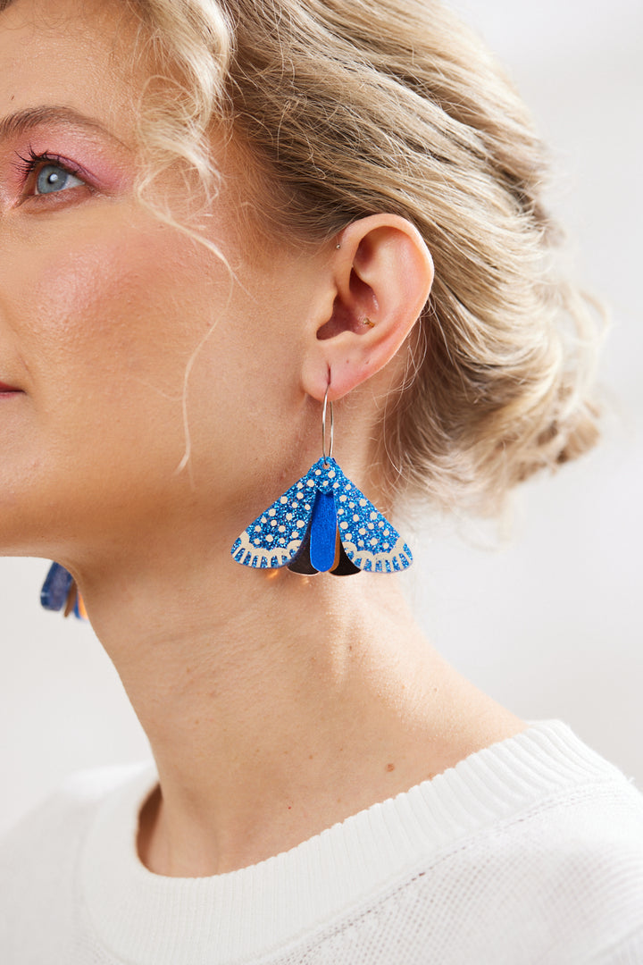 Model wearings Martha Jean Moth Earrings in indigo blue glitter with rose gold