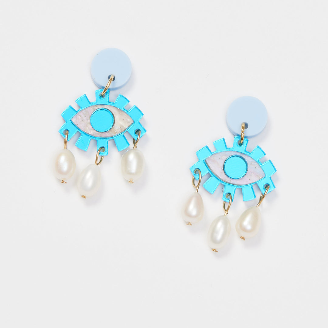 Blue eye earrings with pearl hanging like tears on a white background