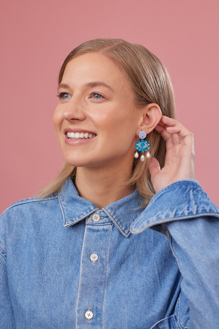 Blue mirrored Eye and pearl earrings on a model  
