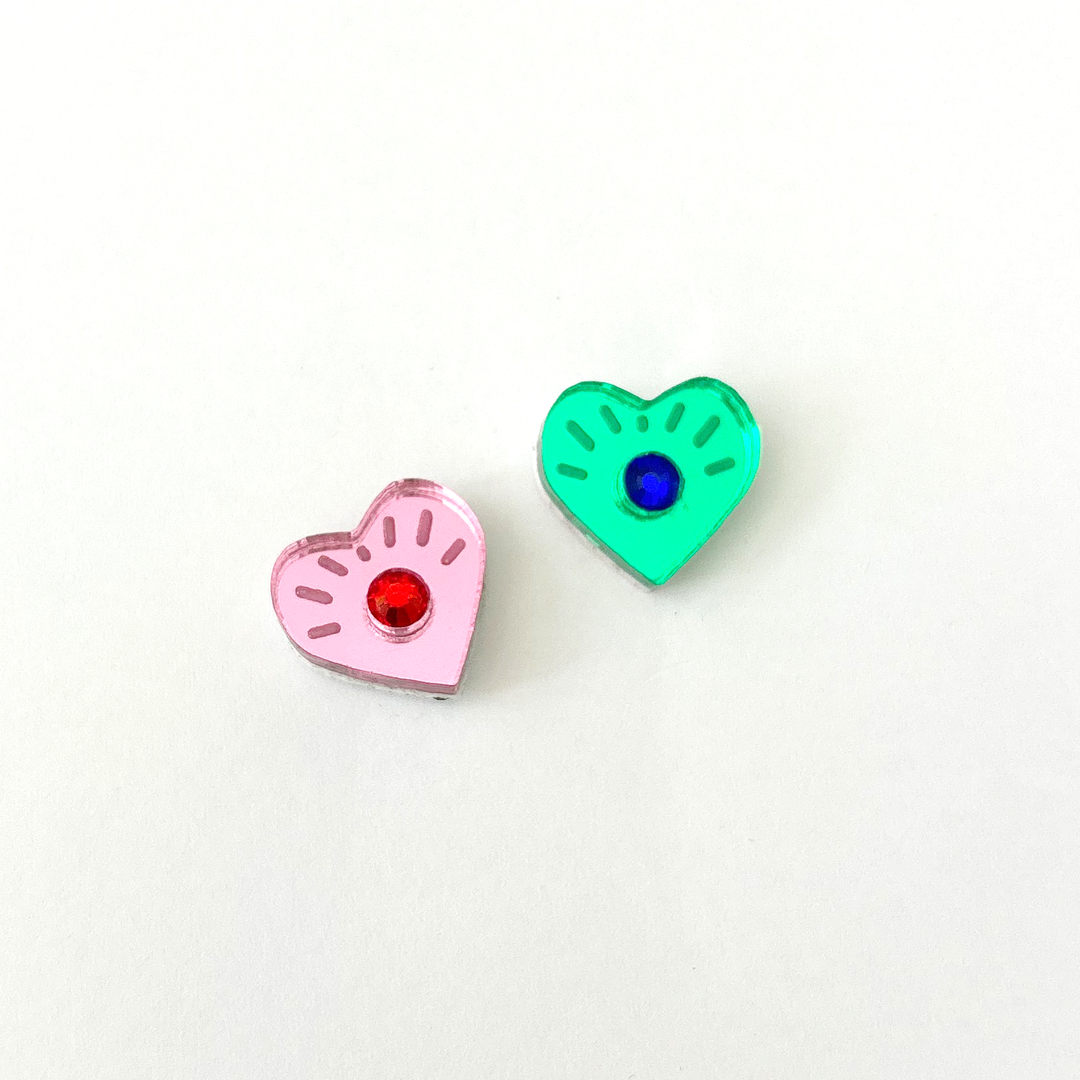 Mismatcehd eye heart studs with crystals in the center on a white background 